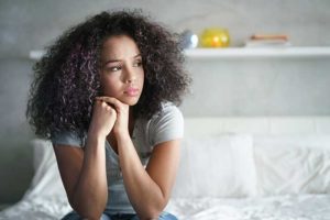 Woman sitting on bed thinking